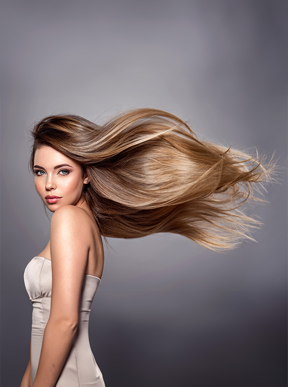 woman with long flowing hair wearing a strapless dress against a grey background showcasing beauty and style with smooth highlights for six times the elegance